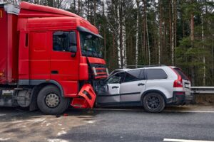 A damaged car after a collision with a heavy truck, set against a blurred transportation background, highlighting the impact of the accident.