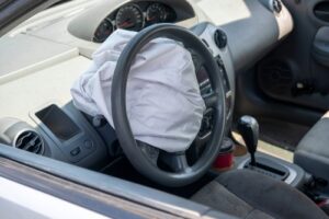 Interior view of a car showing a deployed airbag covering the steering wheel