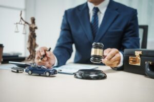 Close-up of a gavel resting on a legal document, with a small car model in the background, symbolizing legal matters related to vehicle accidents.