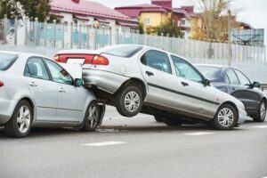 Three damaged cars after a street collision, showing significant impact from a car crash.