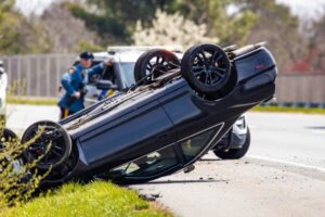 A vehicle rollover on a highway, with emergency responders and police at the scene, assessing the accident and providing assistance.