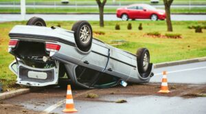 A car crash scene on the street featuring a damaged automobile lying upside down, showcasing the aftermath of the accident.