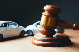 A miniature car model beside a wooden gavel, symbolizing an accident lawsuit or insurance court case.