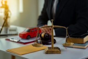 Close-up of a courtroom scene featuring gavels and small toy car models, symbolizing insurance for court claims. Two toy cars are placed on a table, representing a lawyer's service concept related to trial cases.