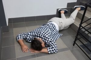 A man lying on stairs after a fall, illustrating potential premises liability under California law.