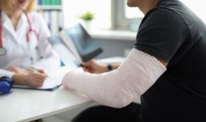 An injured person with a cast consulting a doctor, gathering evidence to support their claim.