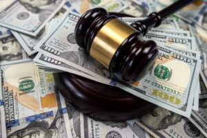 A judge's gavel next to a large stack of dollar bills, representing wrongful death settlement negotiations.