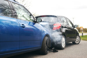 A rear-end collision between two cars with visible damage and smoke, illustrating the aftermath of an accident on the road.