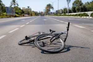 A damaged bicycle lies abandoned in the middle of an empty road, symbolizing a recent accident or cycling-related incident.