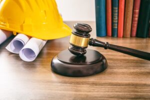 Construction and labor law concept with a judge's gavel and building blueprints on a wooden table, close-up view.