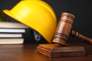 A gavel, legal books, and construction worker's protective gear on a wooden table, captured in selective focus.